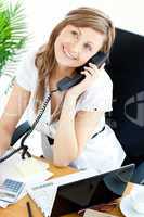 Self-assured businesswoman talking on phone sitting at her desk