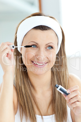 Glowing young woman using mascara