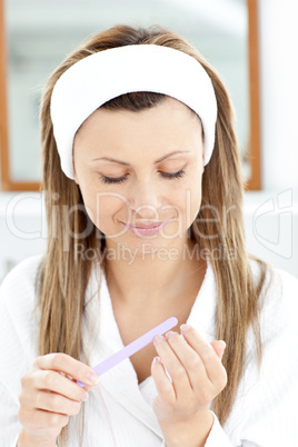 Beautiful woman filing her nails in the bathroom