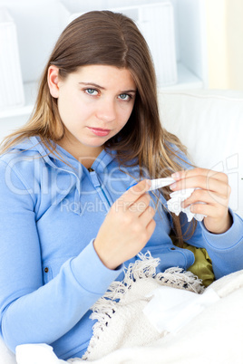 Sick woman holding tissues sitting on a sofa