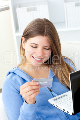 Delighted woman holding a card and a laptop