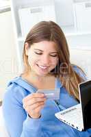 Delighted woman holding a card and a laptop