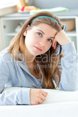 Bored young woman holding a remote in the kitchen