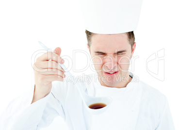Young male chef tasting a soup with distorted face