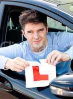 Happy young male driver tearing up his L sign