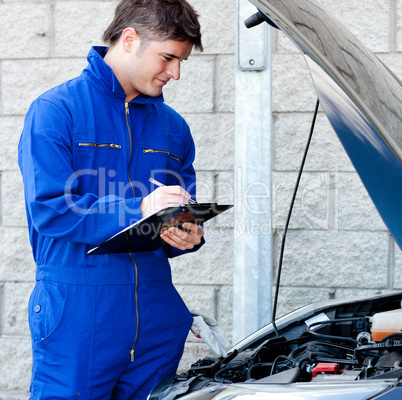 Handsome mechanic writing on a clipboard