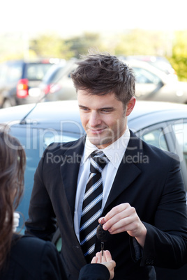 Charming salesman giving a customer car keys