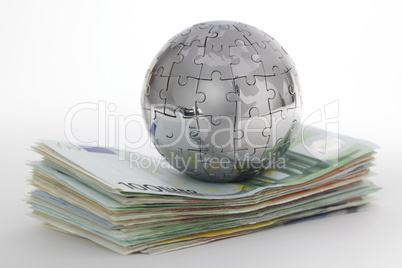 Puzzle- Globus auf Geldstapel