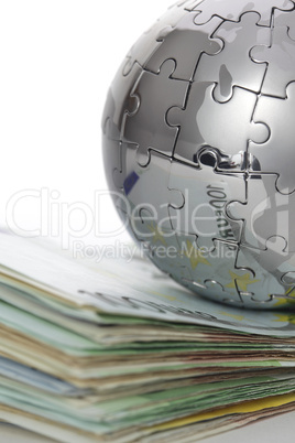 Puzzle- Globus auf Geldstapel