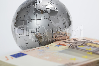 Puzzle- Globus mit Geldstapel