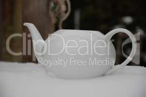 weiße Teekanne im Schnee