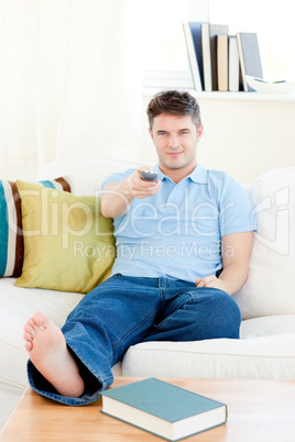 Relaxed young man holding a remote sitting on the couch