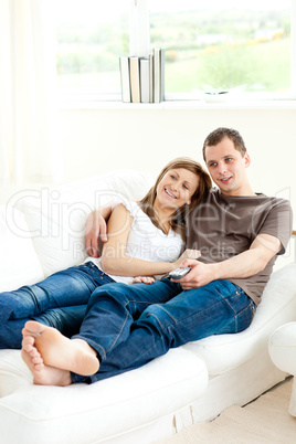 Attentive young couple watching television lying on the sofa