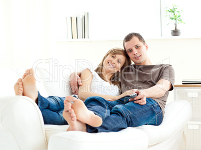 Affectionate couple lying on the sofa watching television