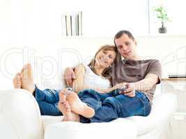 Affectionate couple lying on the sofa watching television