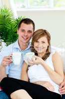 Charming couple holding cups of coffee smiling at the camera