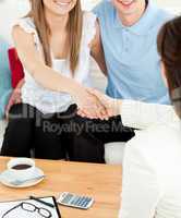 Caucasian young couple shaking hands with a saleswoman