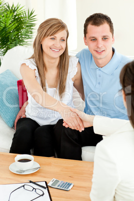 Happy couple concluding a car contract with a female dealer