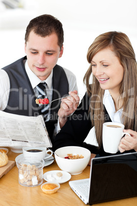 Positive couple of businesspeople having breakfast reading the n