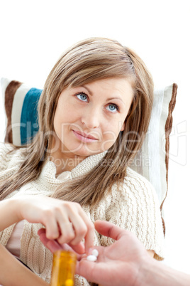 Portrait of a morbid woman taking pills lying on a sofa