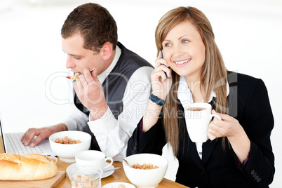 Ambitious businesswoman talking on phone while havin breakfast w