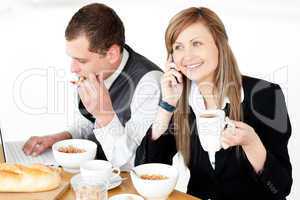 Ambitious businesswoman talking on phone while havin breakfast w