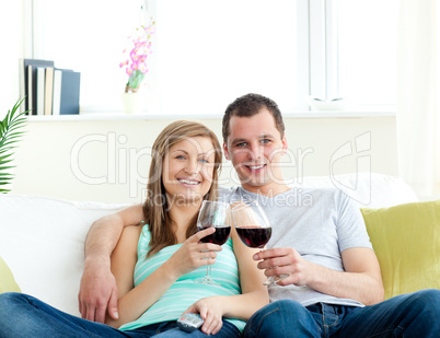 Young embracing  couple sitting on the sofa drinking wine