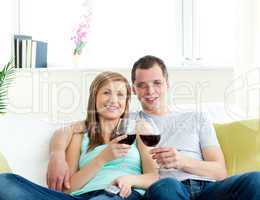 Young embracing  couple sitting on the sofa drinking wine