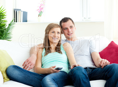 Attentive young couple sitting on the sofa watching tv