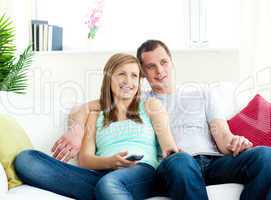 Attentive young couple sitting on the sofa watching tv