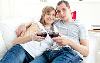 Beautiful young couple lying on the sofa drinking wine