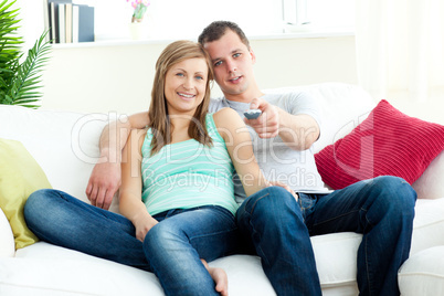 Positive young couple sitting on the sofa watching tv