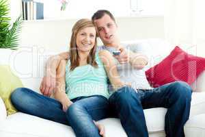 Positive young couple sitting on the sofa watching tv