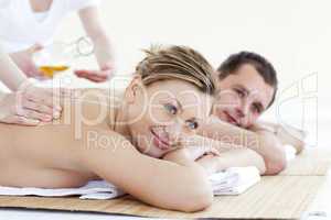 Happy young couple enjoying a back massage with oil in a health spa