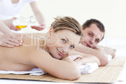 Positive young couple receiving a back massage with oil