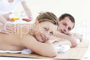 Positive young couple receiving a back massage with oil