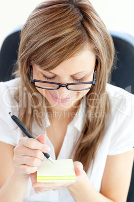 Happy businesswoman taking notes sitting in her office