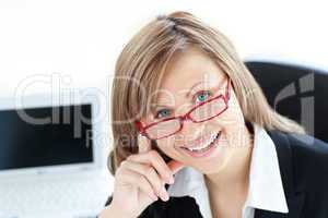 Merry businesswoman looking at the camera sitting in her office