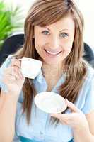 Portrait of a delighted businesswoman holding a cup smilling at