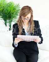 Concentrated businesswoman reading the newspaper sitting on the