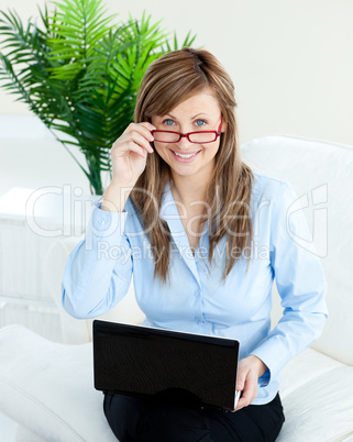 Sophisticated businesswoman using a laptop smiling at the camera