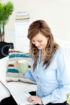 Pretty caucasian businesswoman using her laptop on the sofa