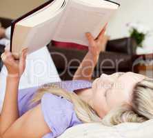 Relaxed young woman reading a book lying on the floor