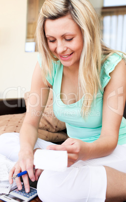 Bright young woman using her calculator holding a bill