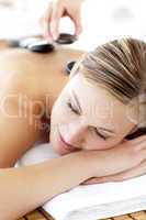Charming young woman enjoying a back massage with hot stone