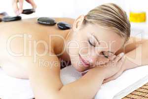Cute young woman enjoying a back massage with hot stone