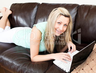 Positive caucasian woman using her laptop on the sofa