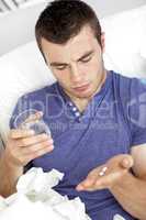 Depressed young man taking pills with water