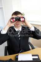 Caucasian young businessman looking through binoculars