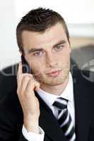 Assertive young businessman talking on phone looking at the came